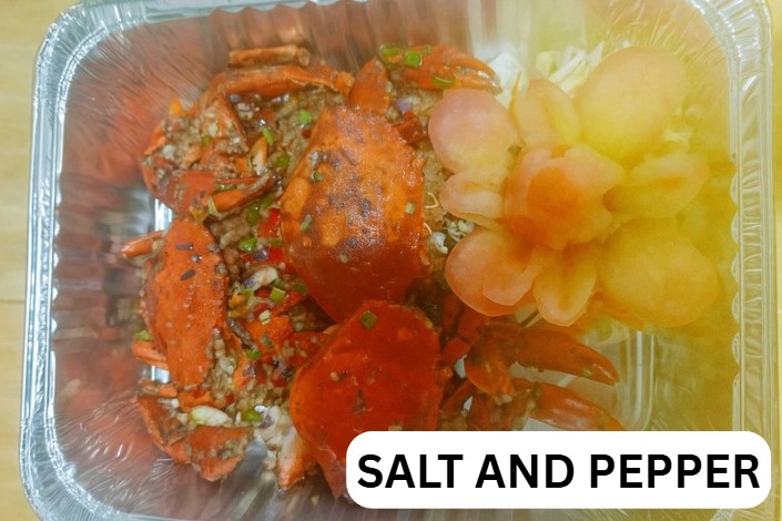Salt and pepper crab topped with chili and scallions, served on a white plate